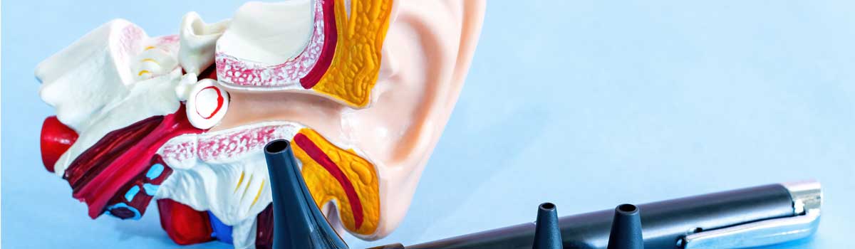 Modello anatomico dell'orecchio con otoscopio e speculum su sfondo blu